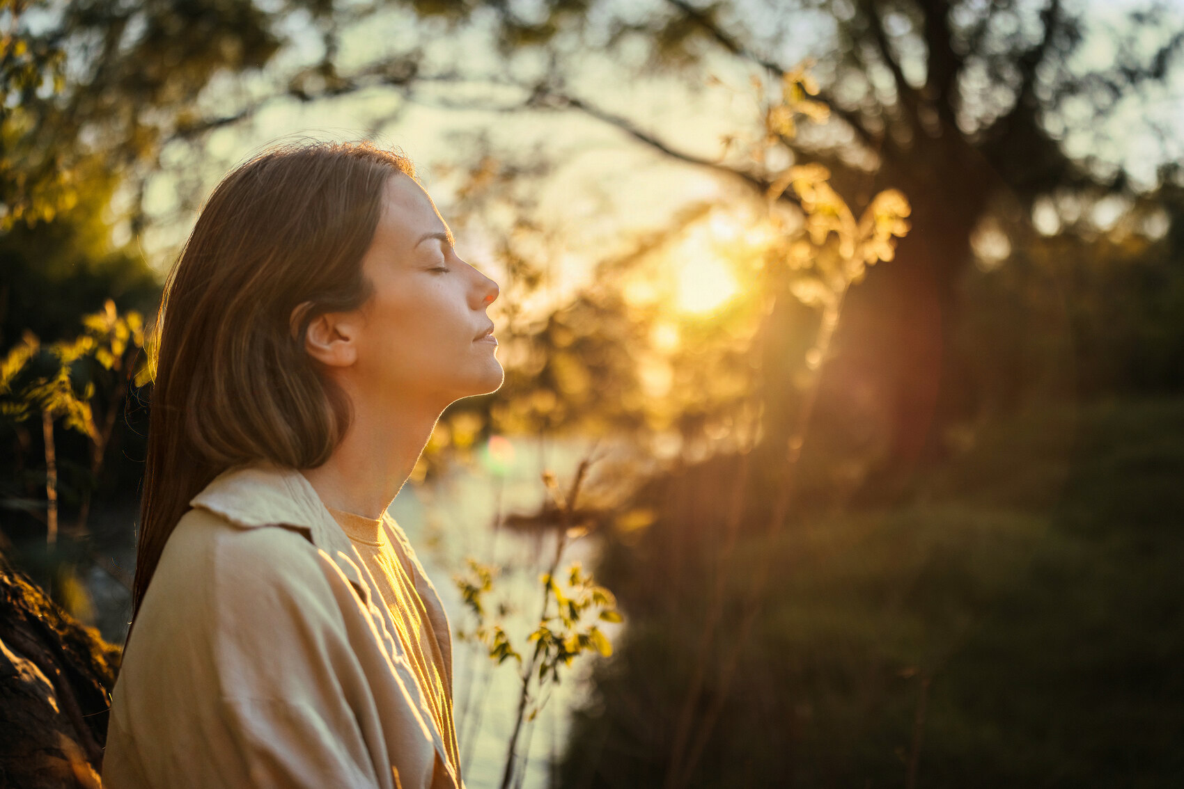A woman resting with her eyes closed in golden evening light
