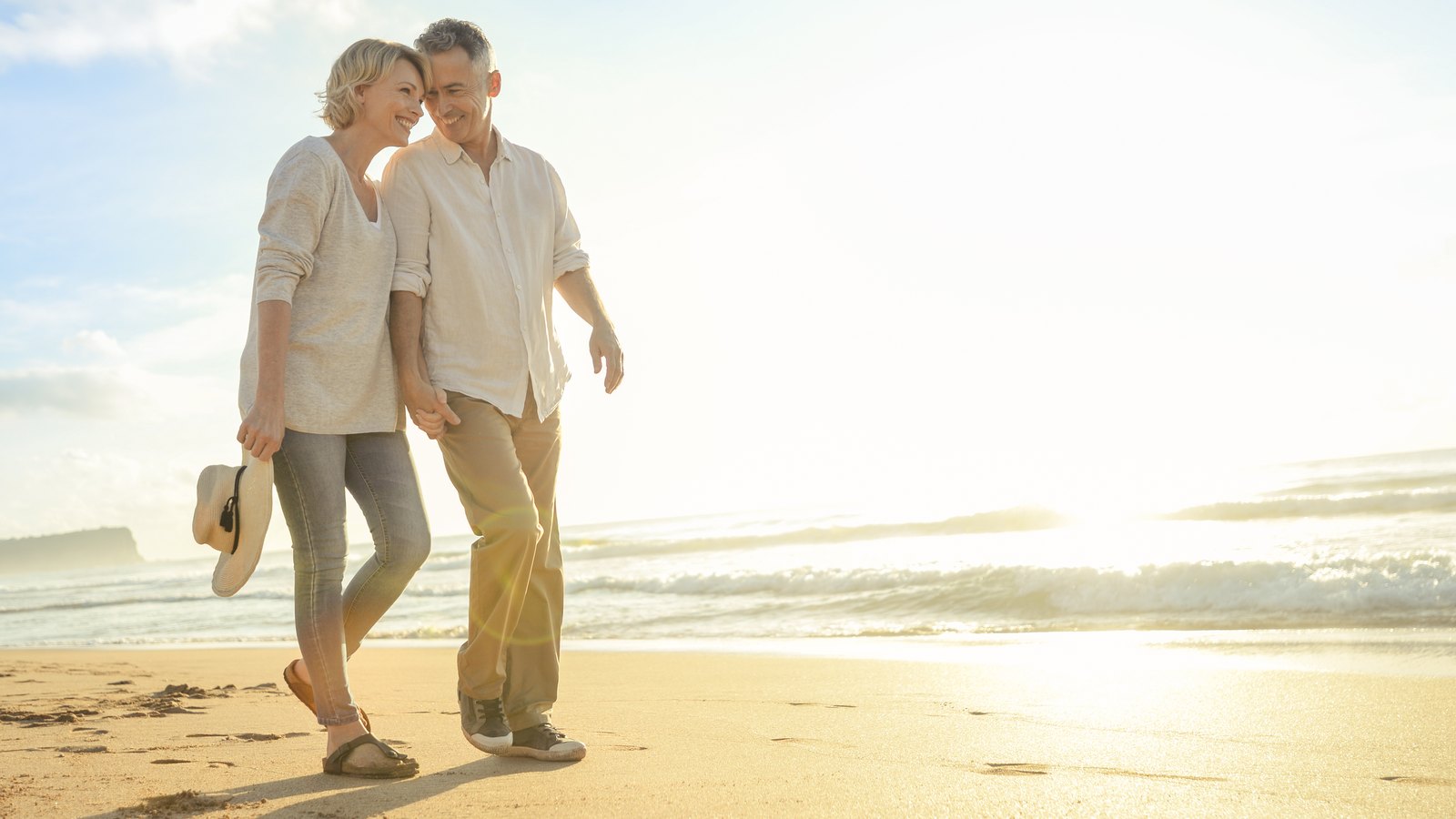 A couple walking together on a beach at sunrise